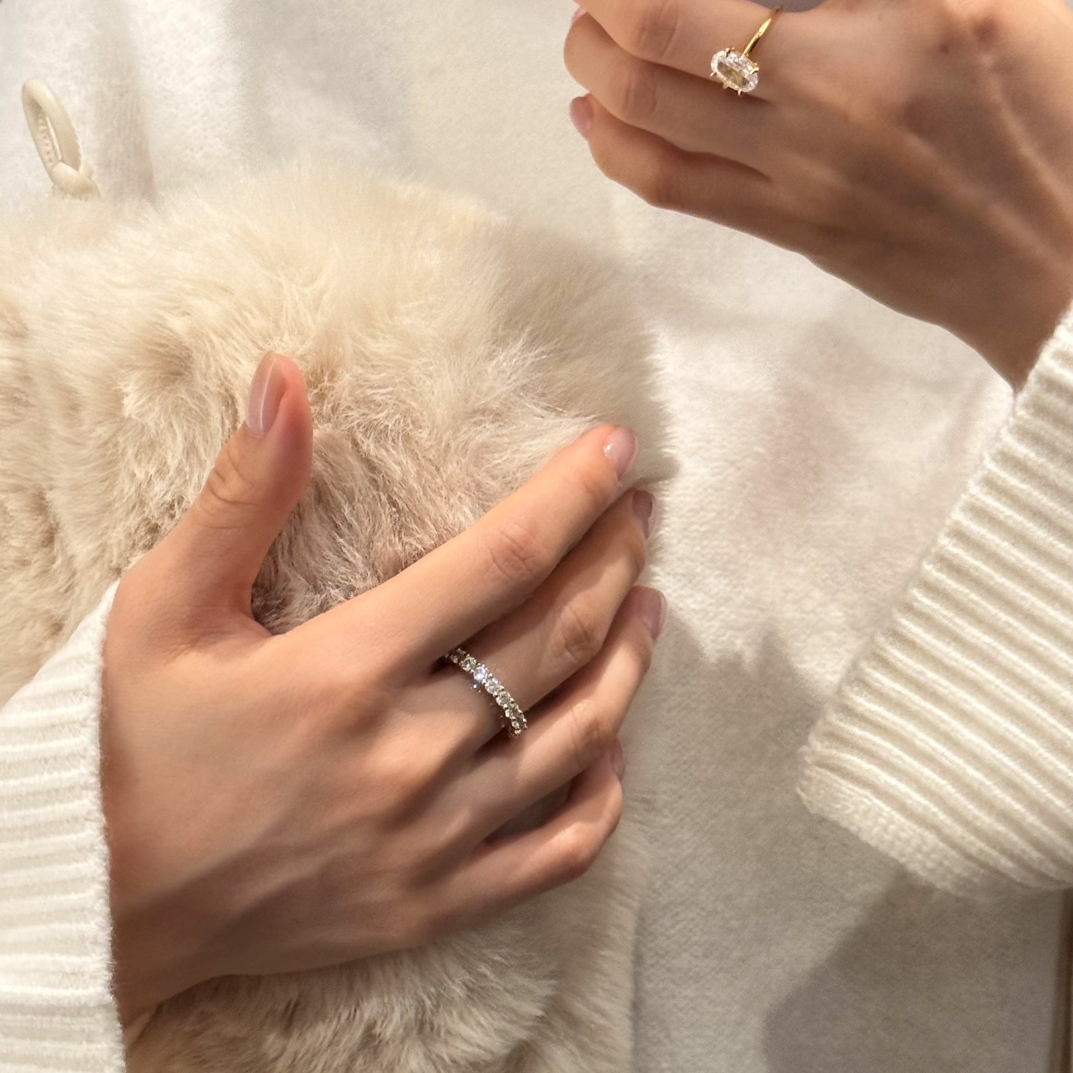 Dues Ring worn on left hand, Vera Ring and Ciel Ring worn on right hand — sparkly 18k plated on sterling silver rings from LUME styled with white knit top and soft fluffy bag
