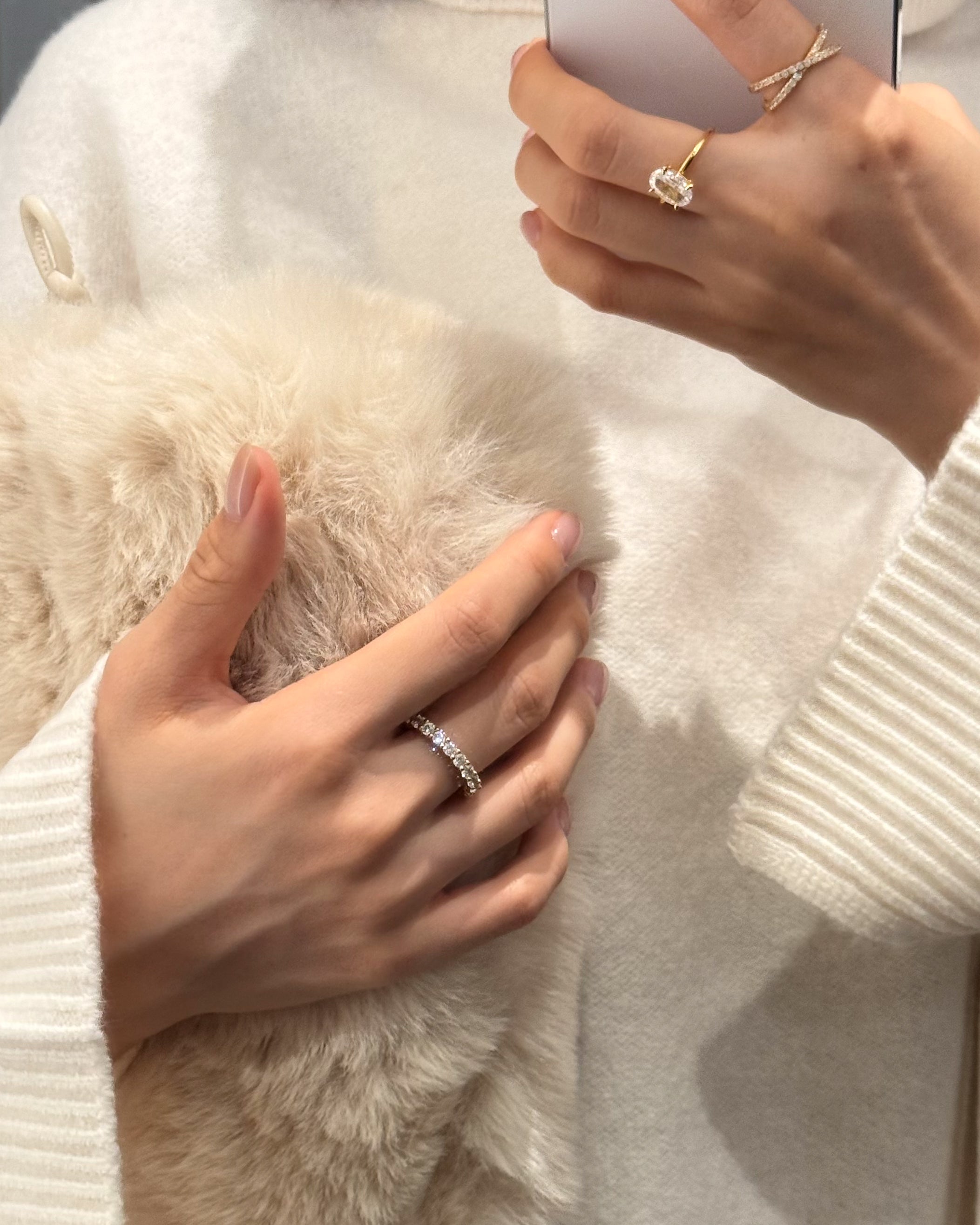 Dues Ring worn on left hand, Vera Ring and Ciel Ring worn on right hand — sparkly 18k plated on sterling silver rings from LUME styled with white knit top and soft fluffy bag