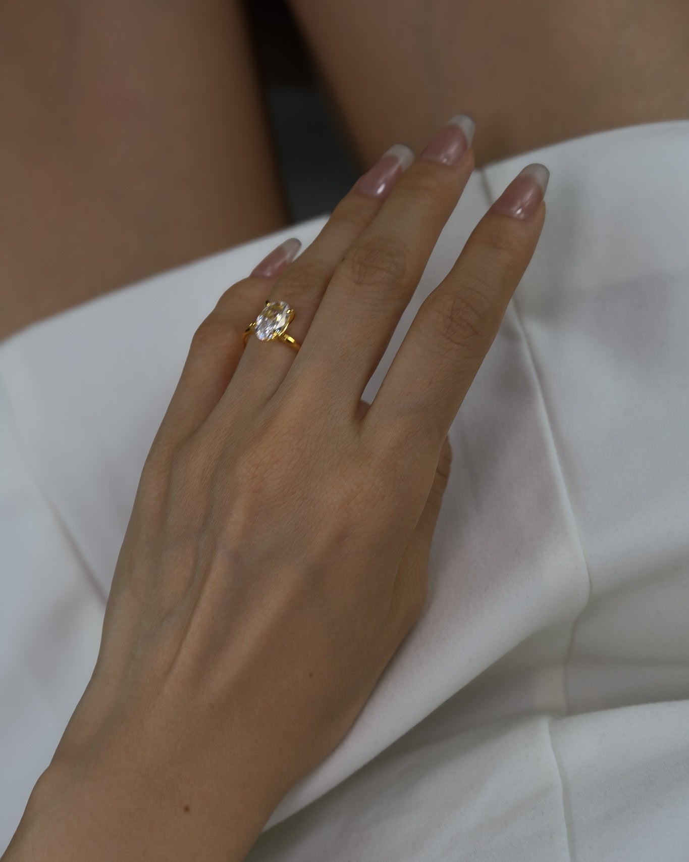 Hand wearing a ciel ring on a white dress