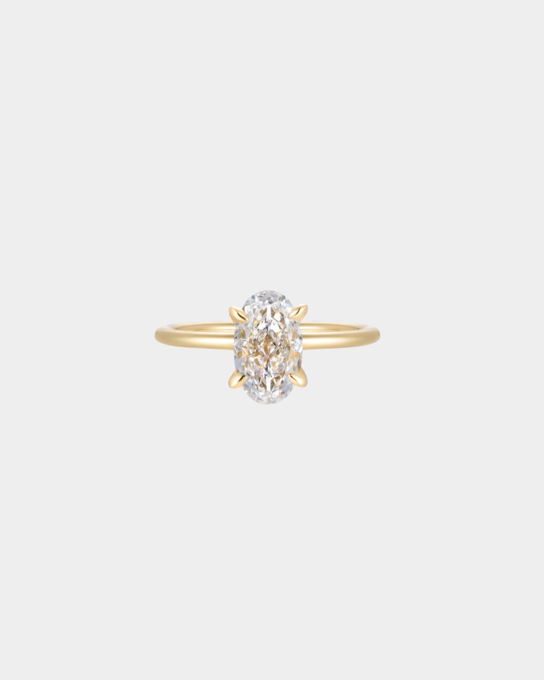 Gold ring with a oval shaped diamond on a light gray background