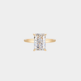 Gold ring with a rectangle shaped diamond looking centre stone on a light grey background