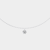 Delicate silver necklace with a small diamond pendant on a light gray background