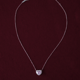 Silver necklace with a heart-shaped pendant on a dark red background
