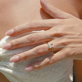 Close-up of a hand wearing lume jewellery's elodie diamond ring on a light fabric background