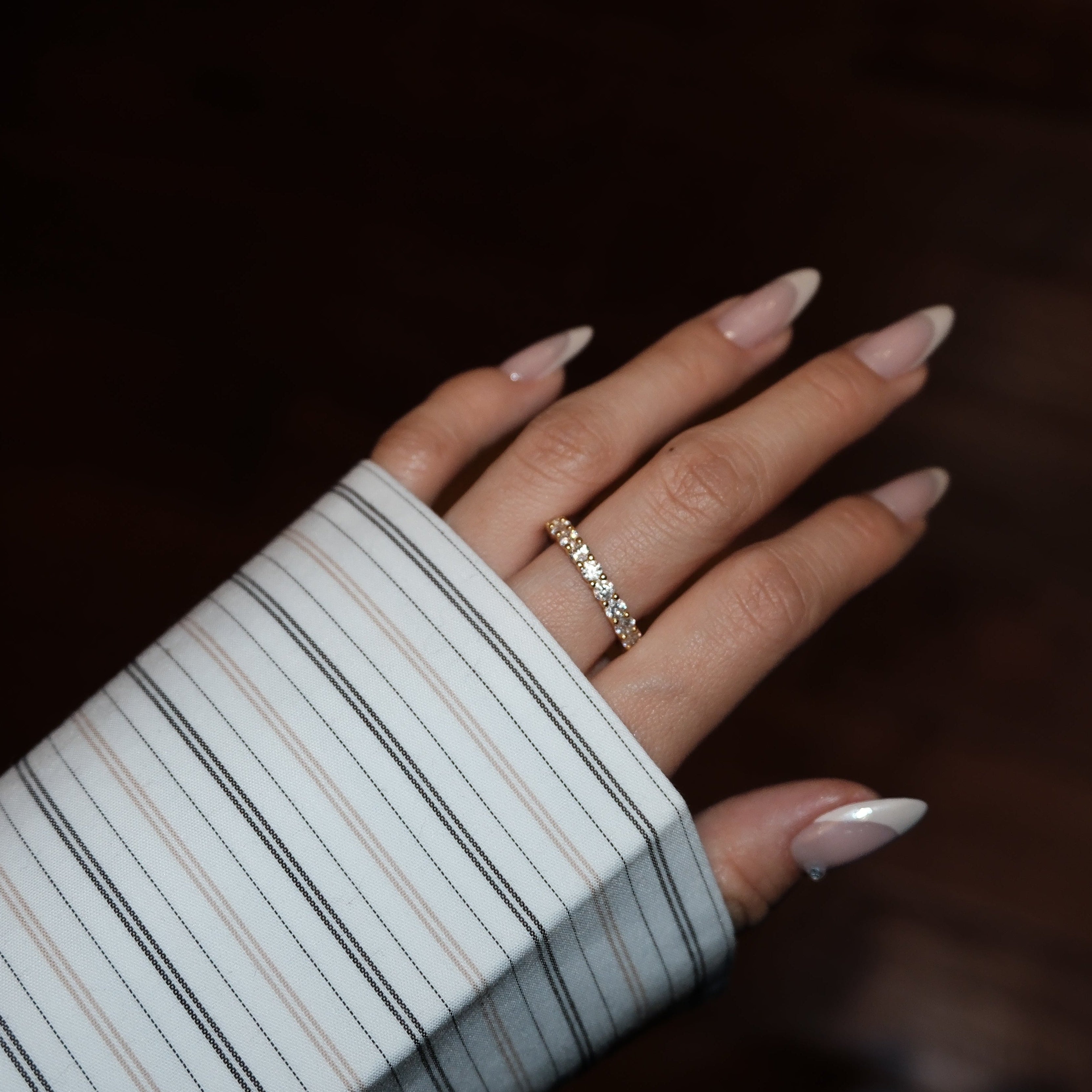 Hand with lume jewellery's dues gold ring on a dark background