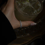 Hand holding a drink with a ring on a dark surface