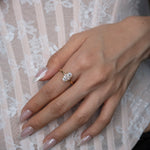 Hand wearing a diamond ring on a lace fabric background