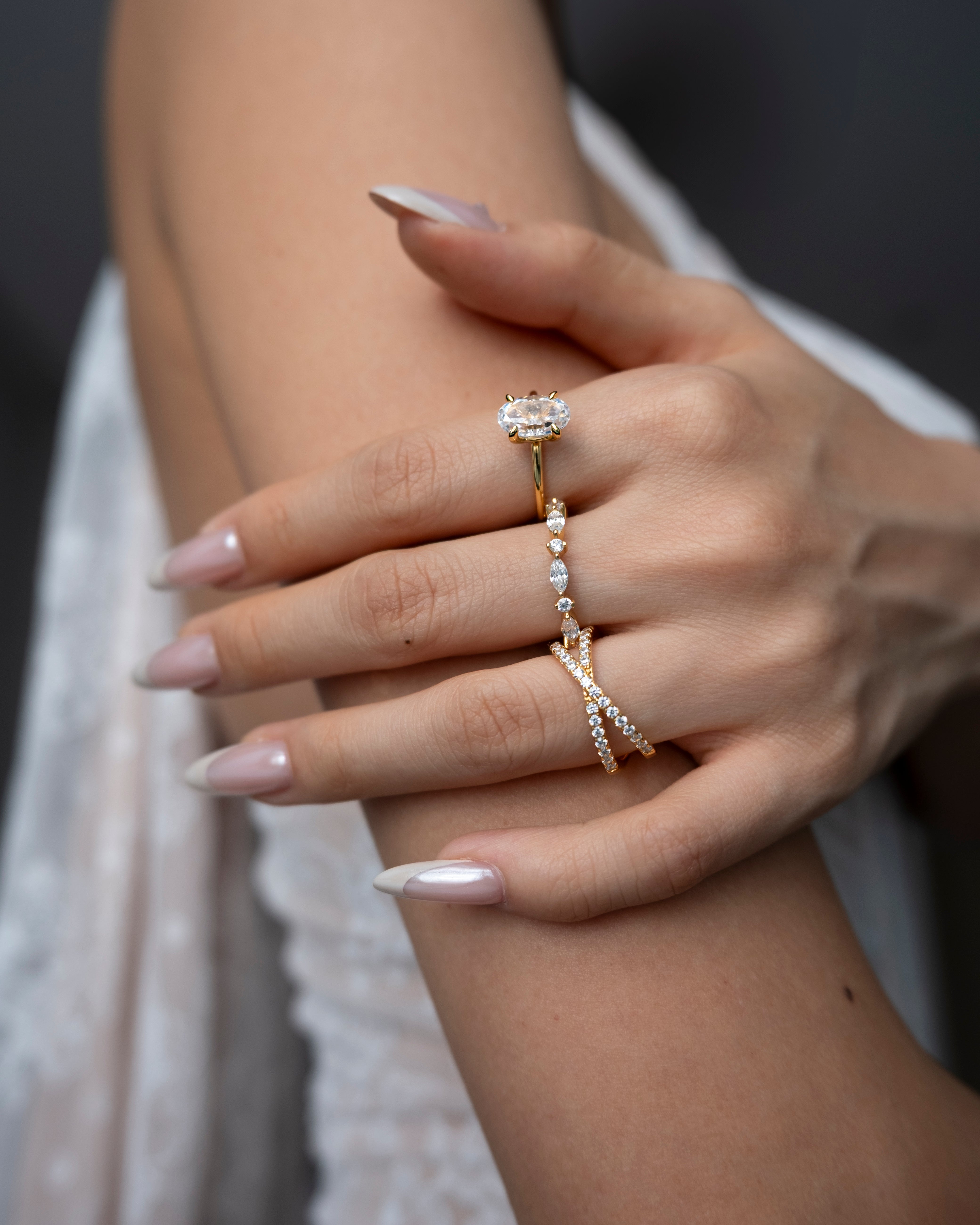Close-up of a hand wearing ciel ring, celeste ring and vera ring with a blurred background