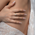 Close-up of a hand wearing a diamond ring on a blurred background