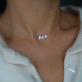 Trio Necklace with three small pendants on a person wearing a light-colored sweater.