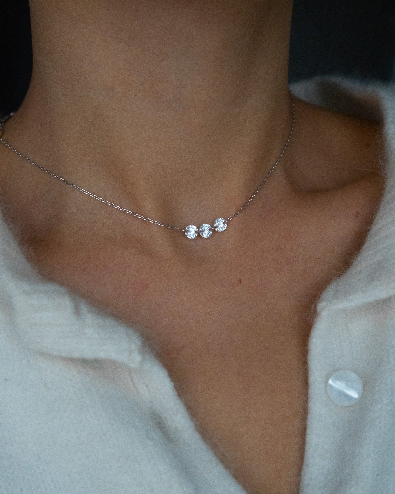 Trio Necklace with three small pendants on a person wearing a light-colored sweater.