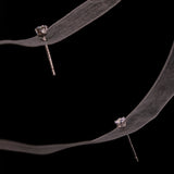 Pair of LUME's Stella stud earrings on a black background