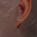 Close-up of an ear with a Mossanaite stud on a textured brown beige background