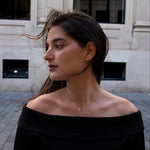 Woman wearing a black off-shoulder top with lume jewellery mono necklace and lume jewellery stella studs