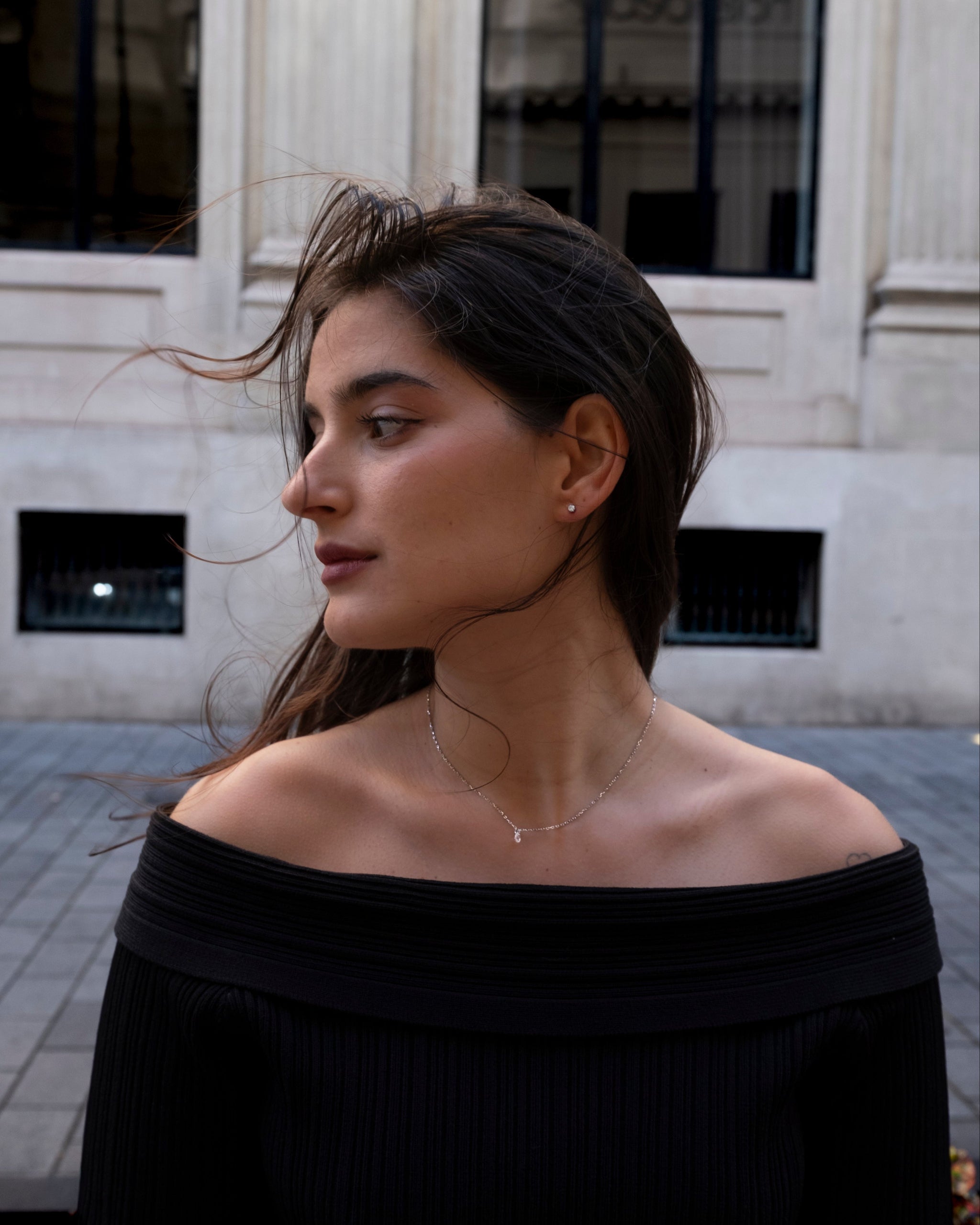 Woman wearing a black off-shoulder top with lume jewellery mono necklace and lume jewellery stella studs