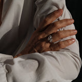 Close-up of a hand wearing an aurora diamond ring with a blurred background