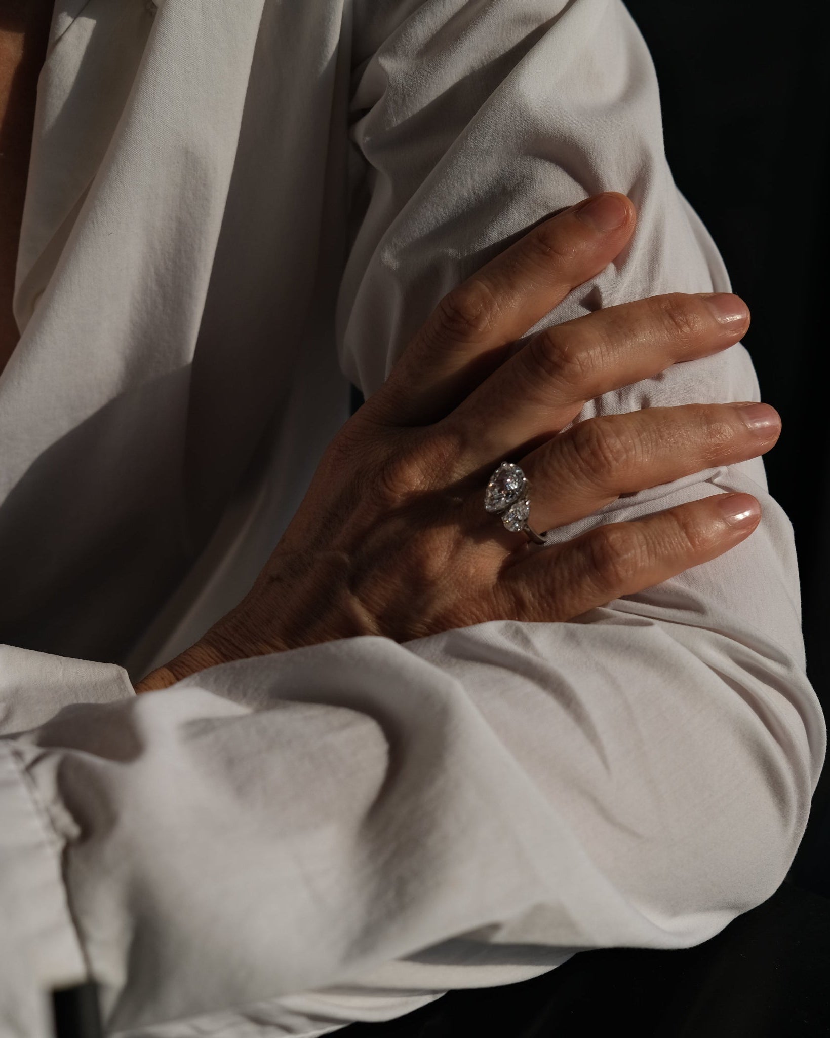 Close-up of a hand wearing an aurora diamond ring with a blurred background