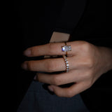 Close-up of a hand wearing lume's elodie ring and dues ring with a dark background