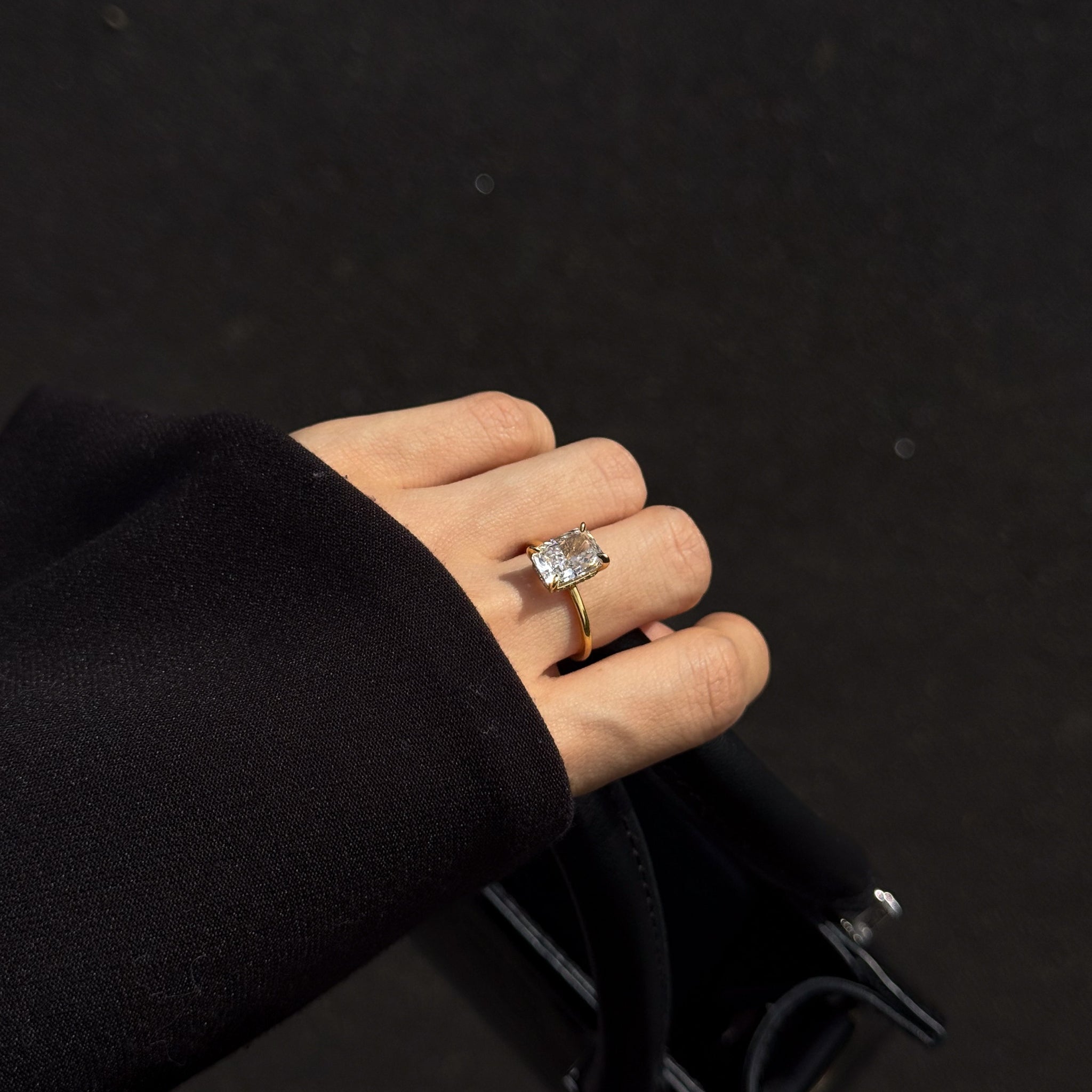 elodie ring on a hand holding a black back 