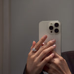 hand wearing aurora ring holding a white phone