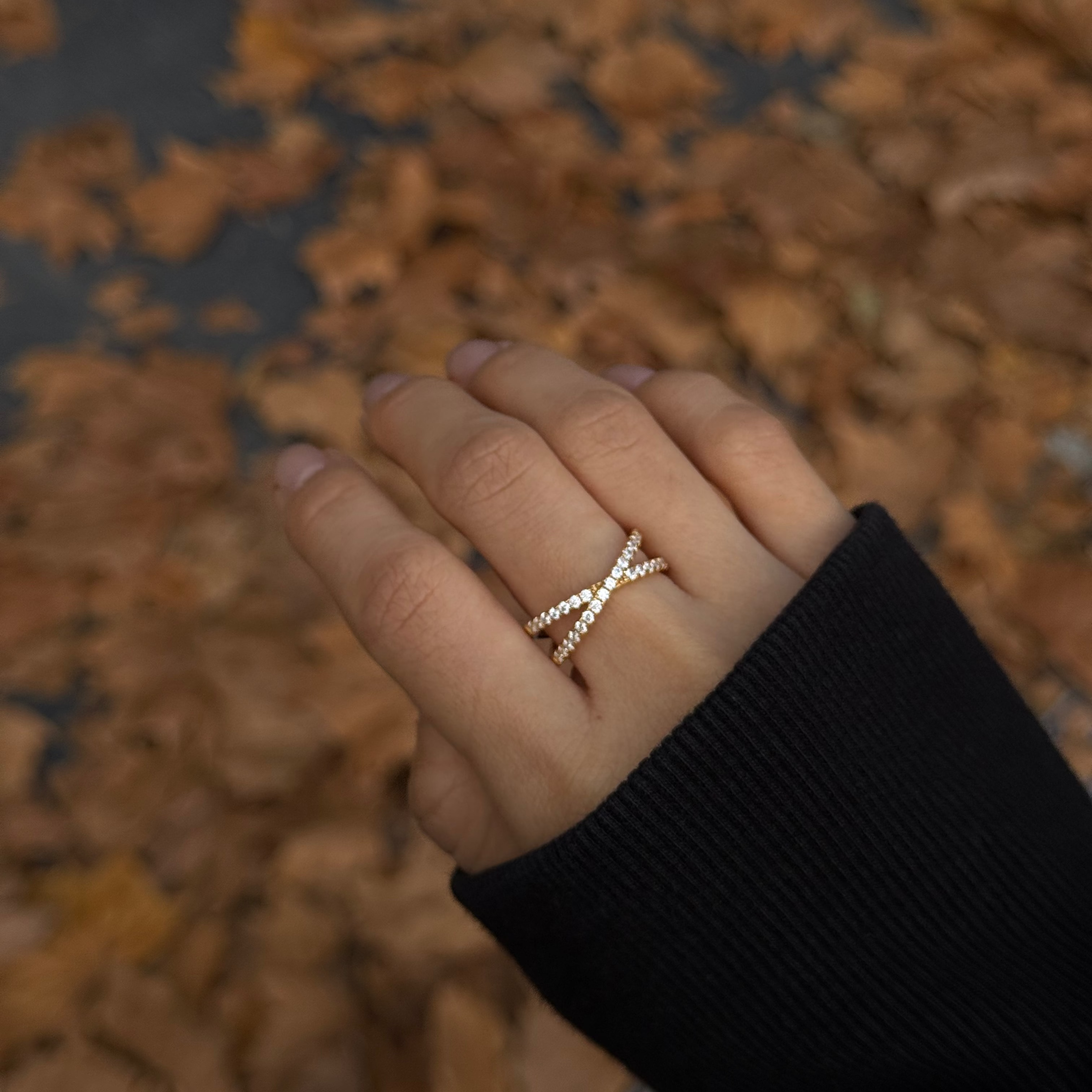 Hand wearing lume jewellery's vera ring with a blurred autumn leaf background