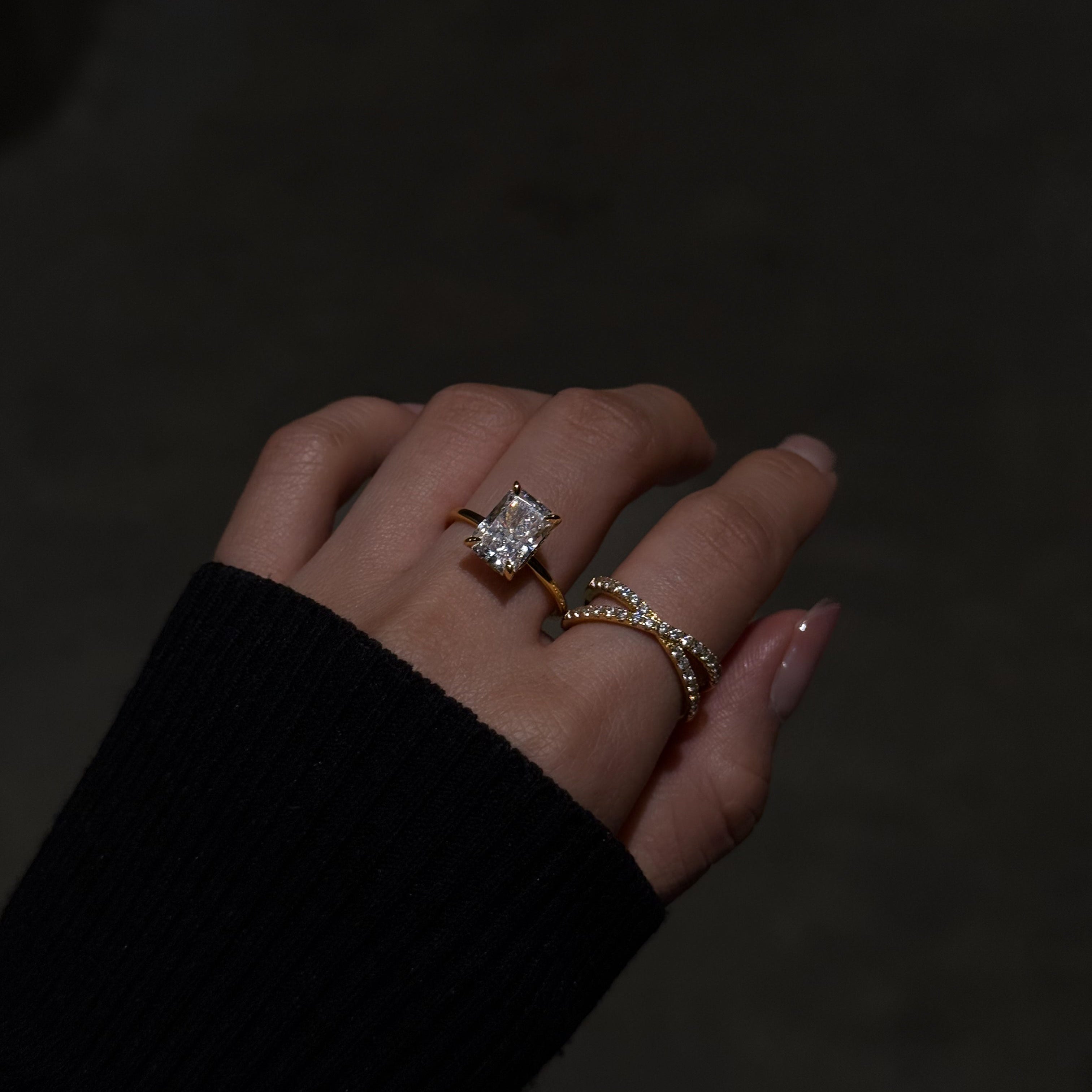 Hand wearing lume jewellery's elodie ring and cross ring on a dark background