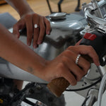 model hands on a bike wearing amore ring and roen ring from lume jewellery