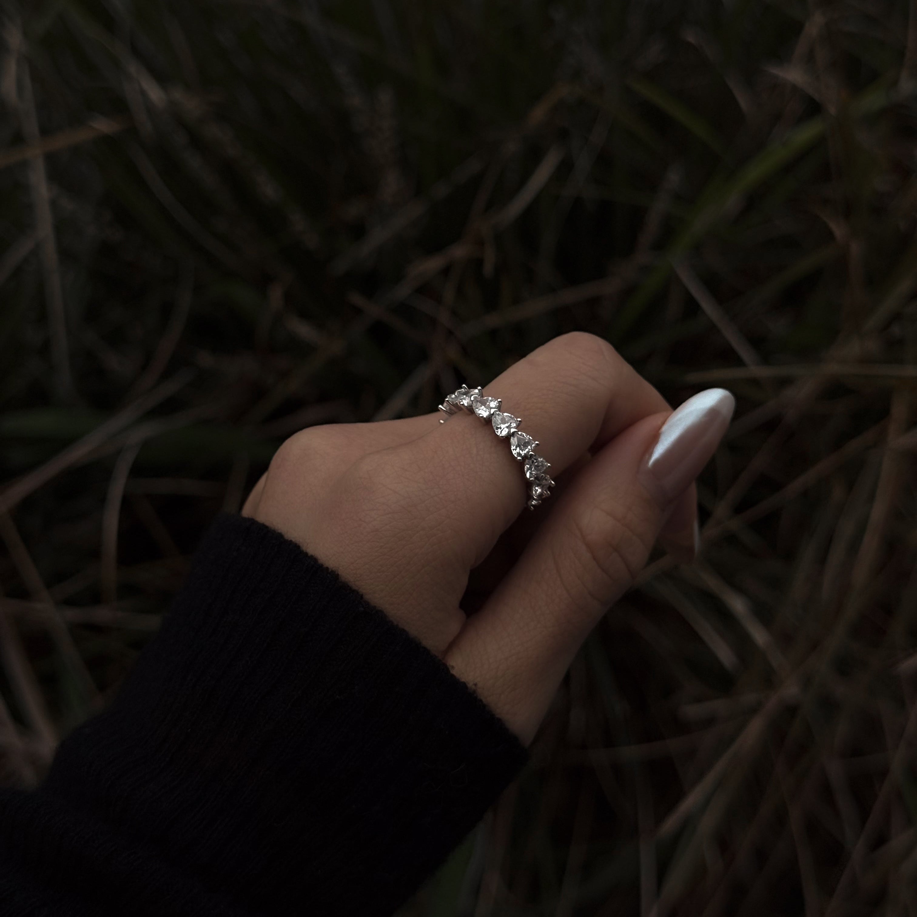 Hand wearing lume jewellery's amore ring with a dark background
