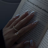 Hand with silver nail polish holding an open book with text.
