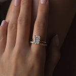 Close-up of a hand wearing a elodie ring and a dues ring on a dark background