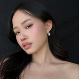 Woman wearing starry teddy earrings against a black background