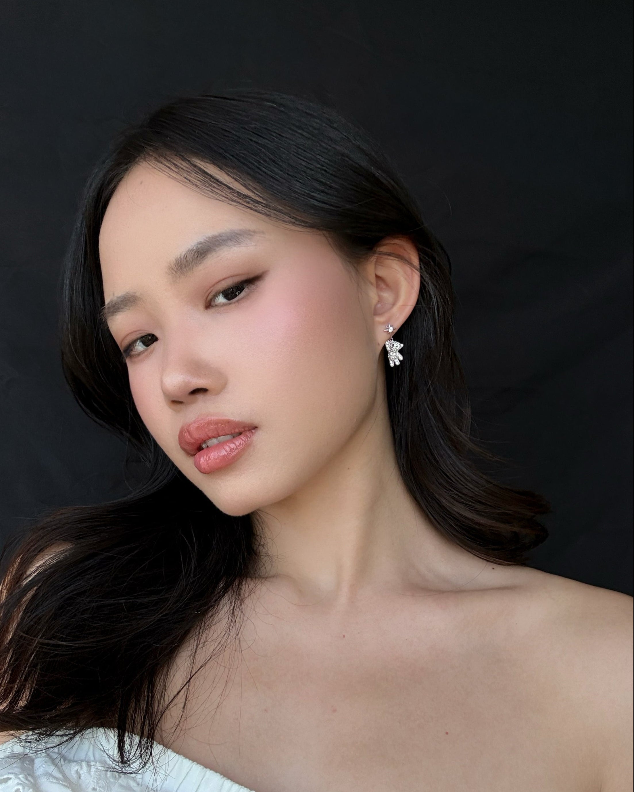 Woman wearing starry teddy earrings against a black background