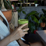 hand holding a drink with celeste ring and ciel ring on model in a cafe