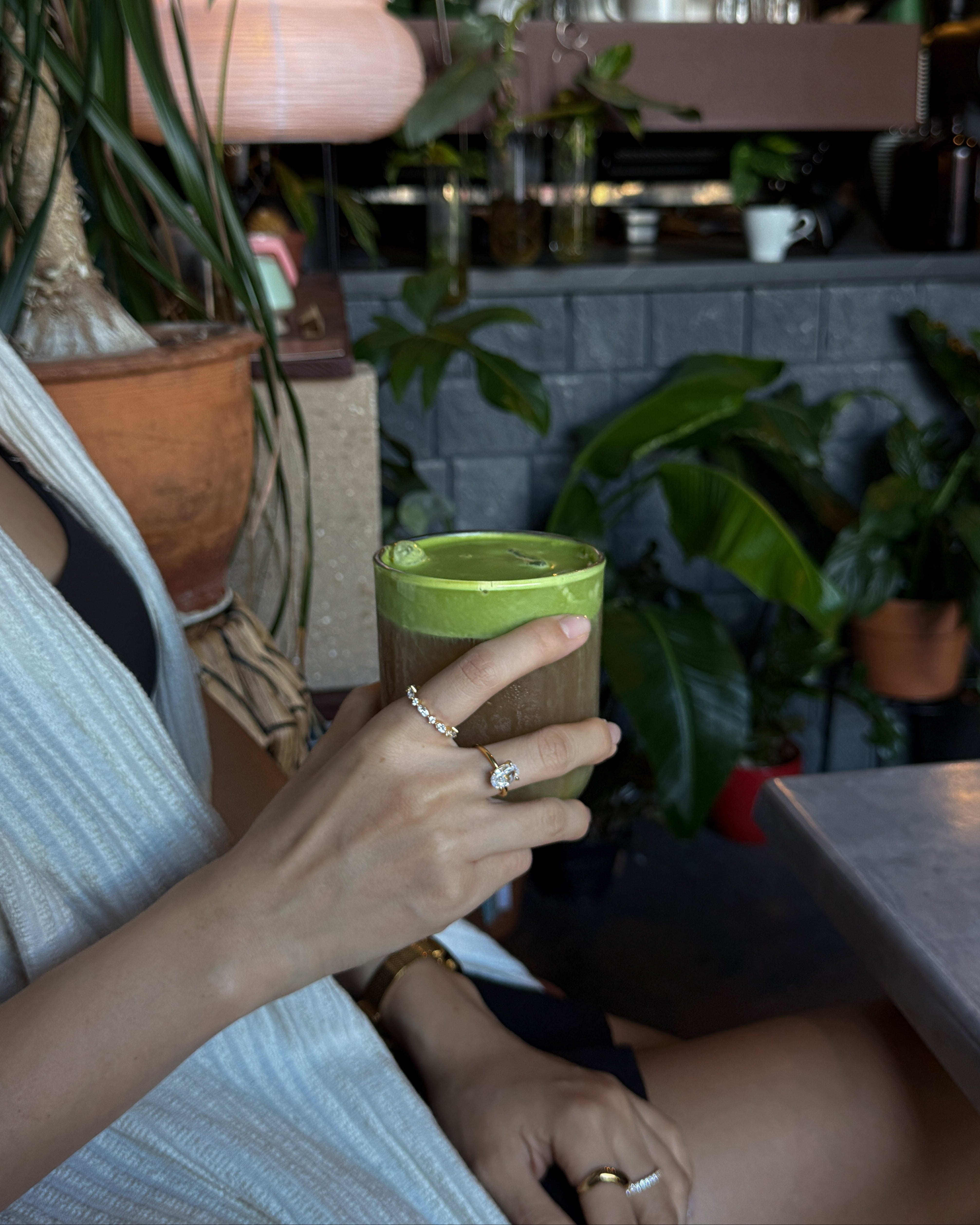 hand holding a drink with celeste ring and ciel ring on model in a cafe