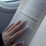 hand wearing dues ring gold and ciel ring from lume jewellery with an open book