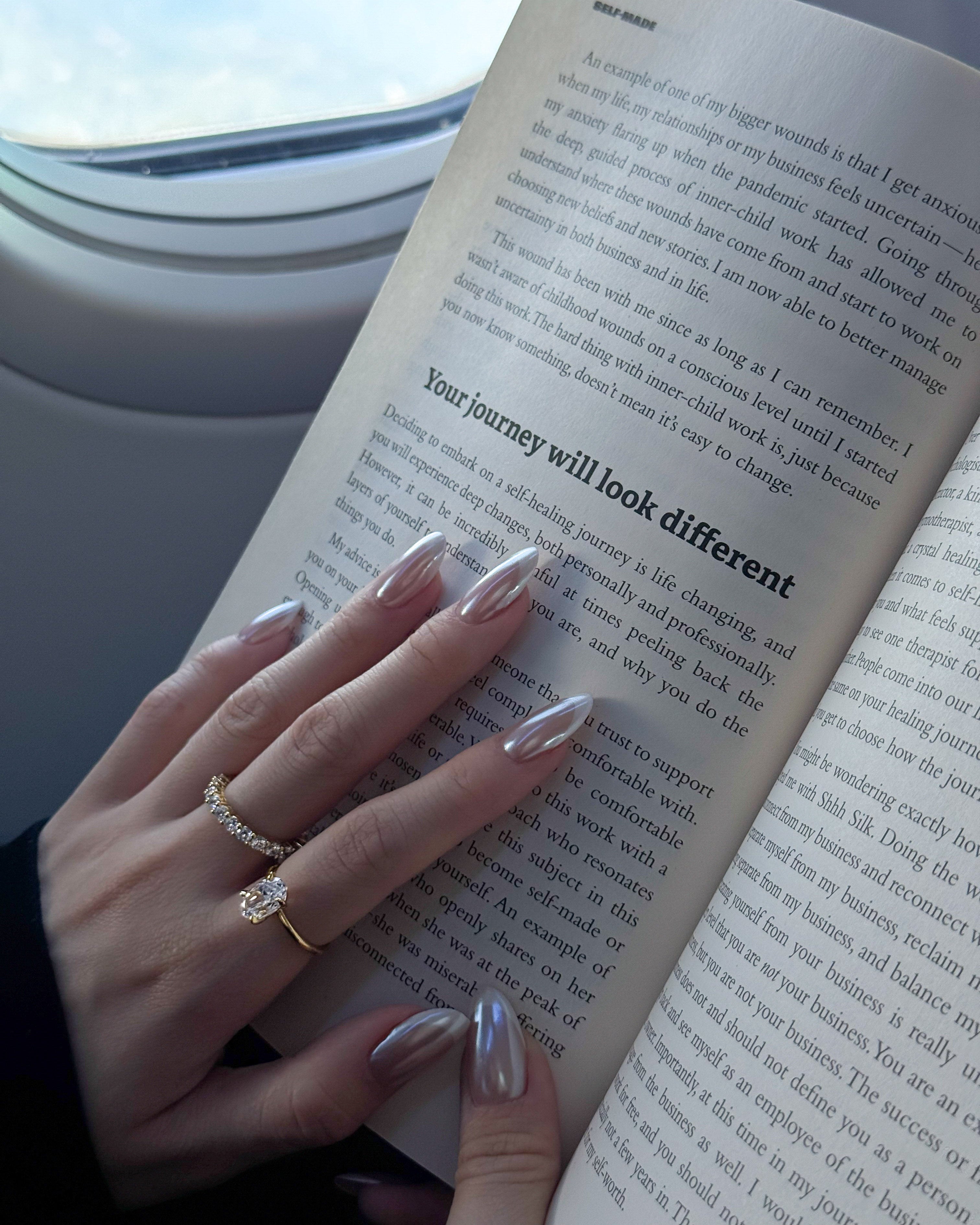hand wearing dues ring gold and ciel ring from lume jewellery with an open book