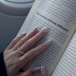 hand wearing dues ring in gold and ciel ring from lume jewellery with an open book