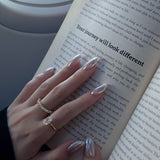 hand wearing dues ring in gold and ciel ring from lume jewellery with an open book