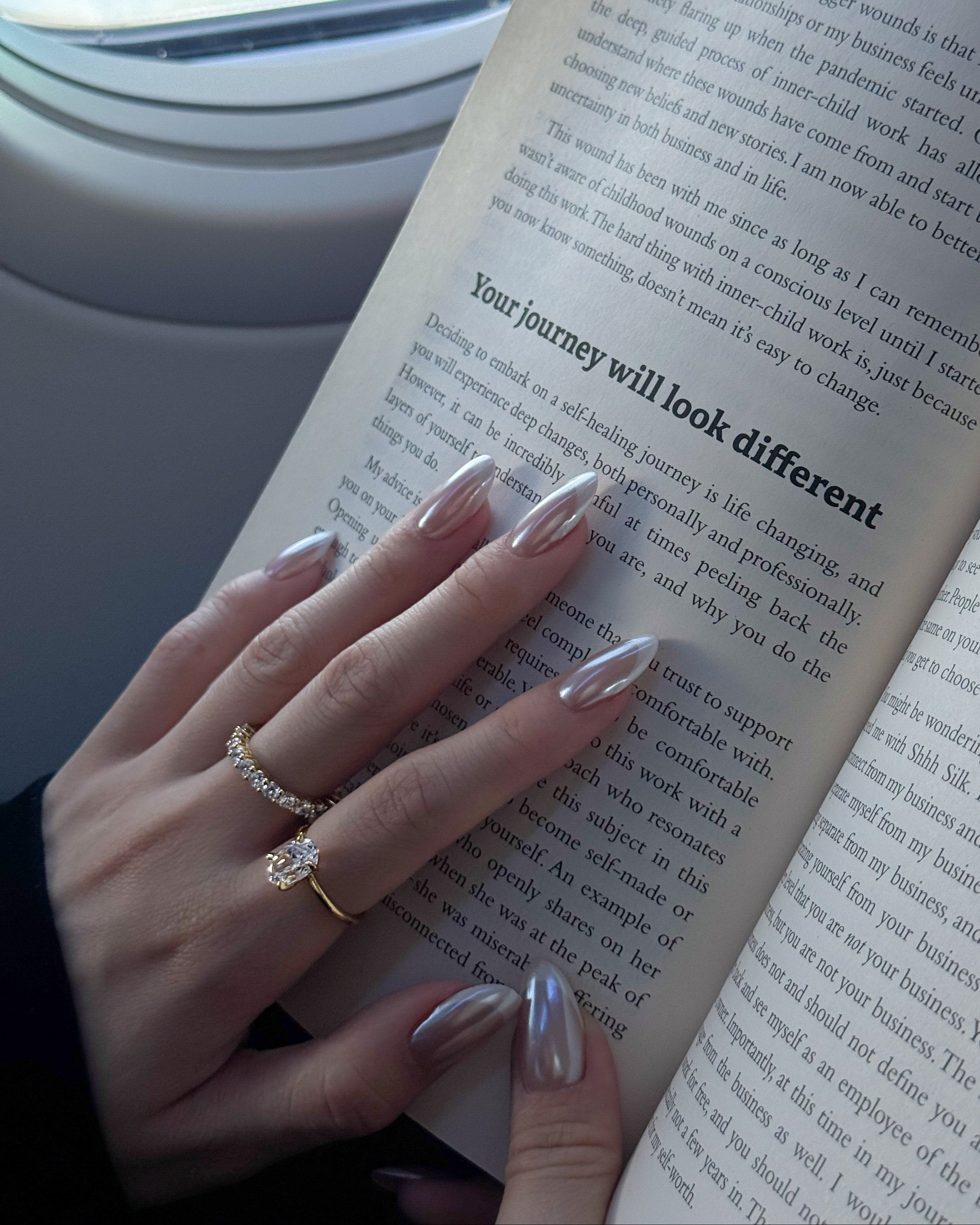 hand wearing dues ring in gold and ciel ring from lume jewellery with an open book