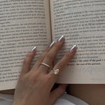 hand wearing a selene ring and a ciel ring with an open book