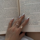 hand wearing a selene ring and a ciel ring with an open book