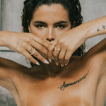 Woman with tattoos on her chest and arms, wearing dues ring in gold and ciel ring