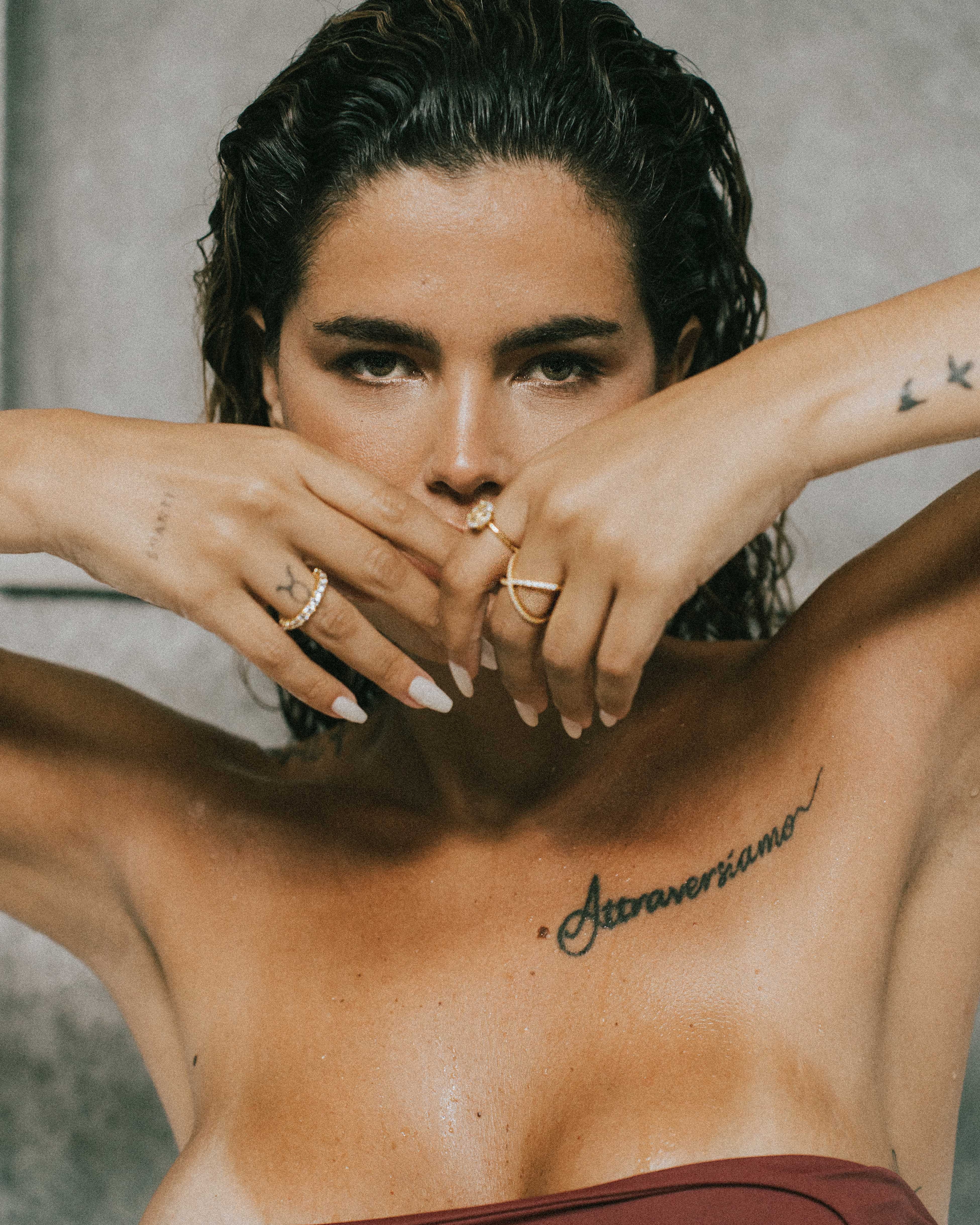 Woman with tattoos on her chest and arms, wearing dues ring in gold and ciel ring