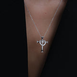 Silver necklace with a cross and heart pendant on a dark background