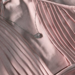 Necklace with a heart pendant on a pink satin fabric background
