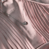 Necklace with a heart pendant on a pink satin fabric background