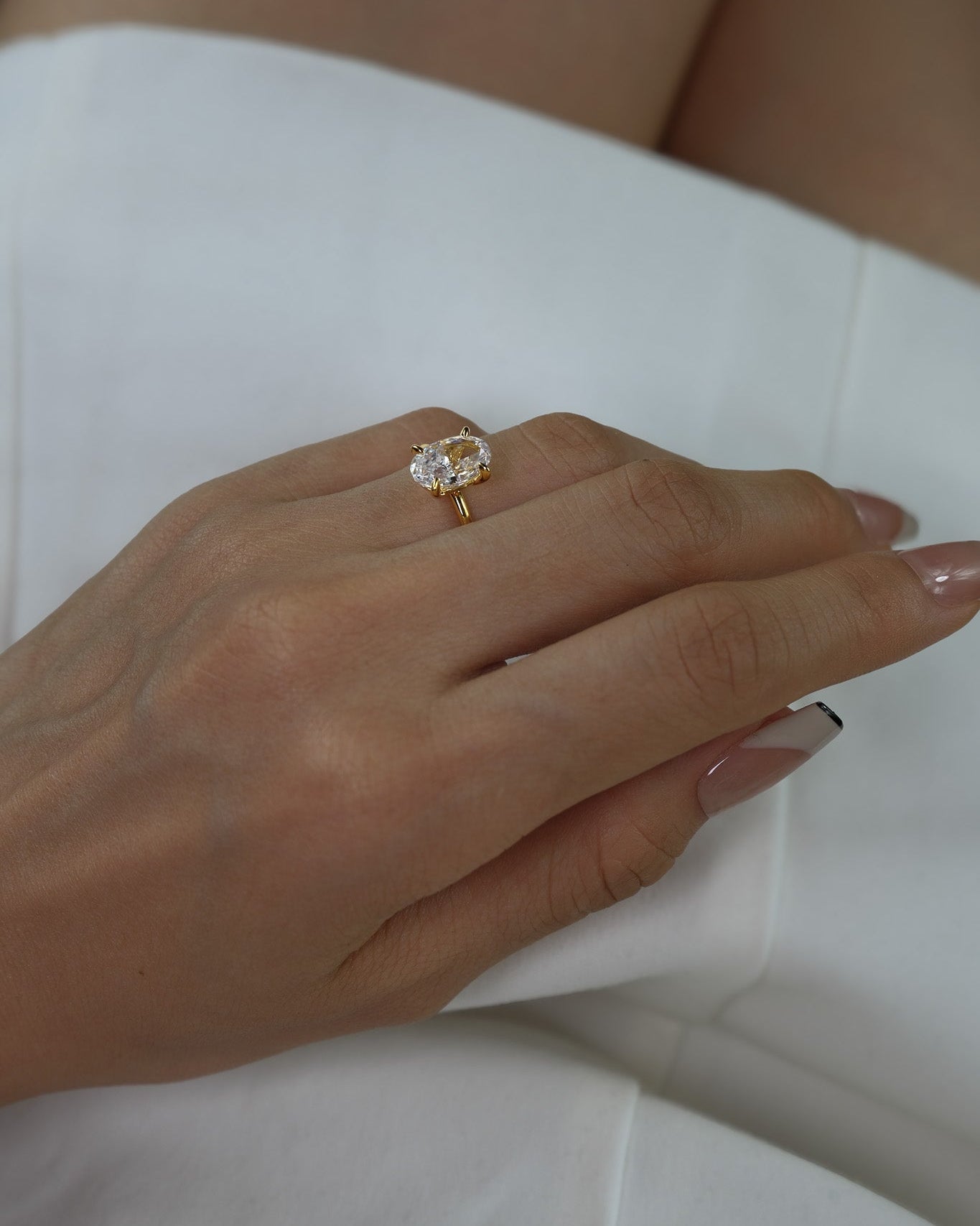 Hand wearing a ciel ring on a white dress