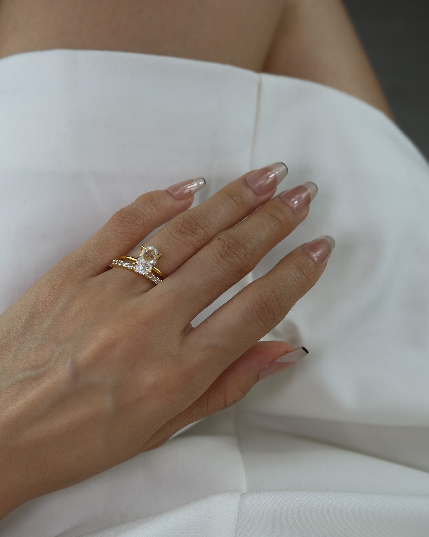 Hand wearing a ciel ring and a selene ring on a white dress