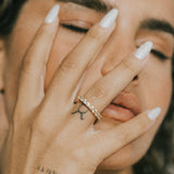 Close-up of a hand with lume jewellery's dues ring, tattoos, and light nail polish.