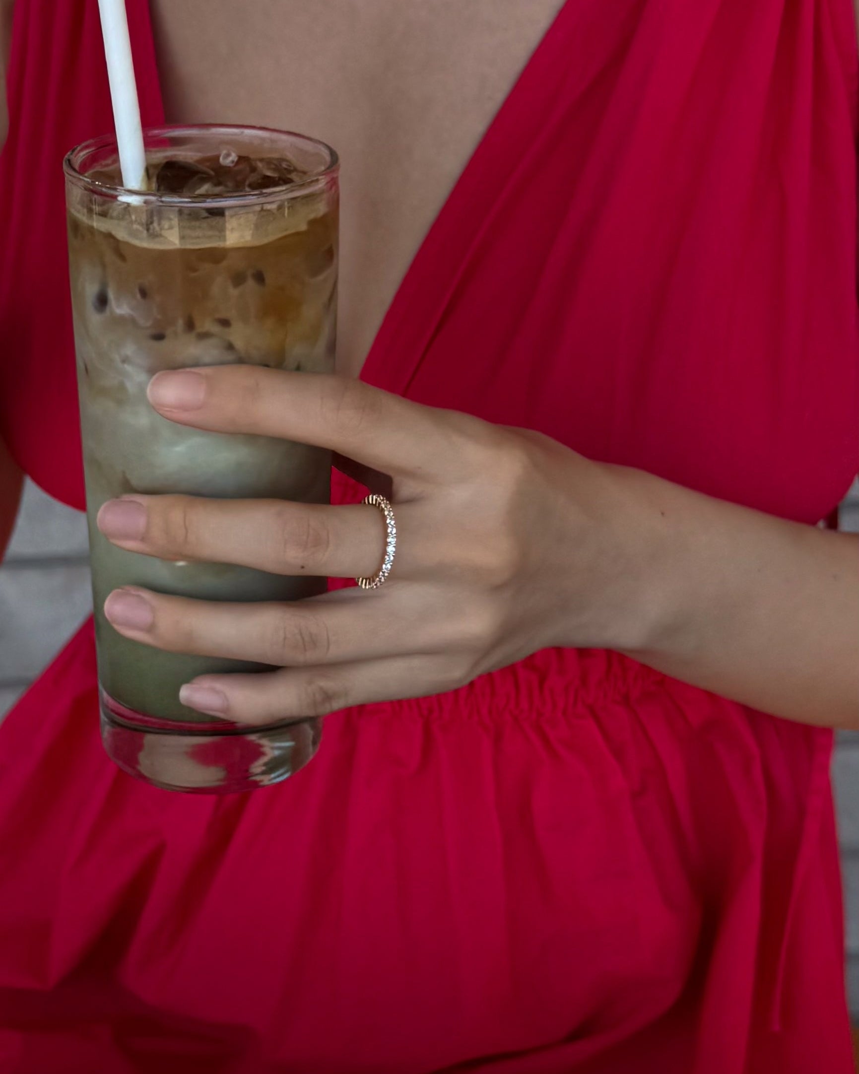hand wearing gold selene ring holding a drink with a red dress on
